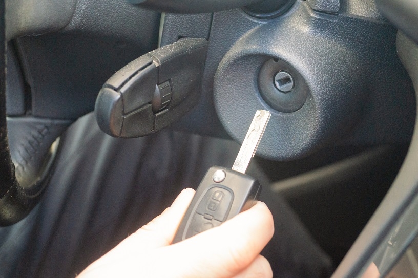 hand holding car key near ignition